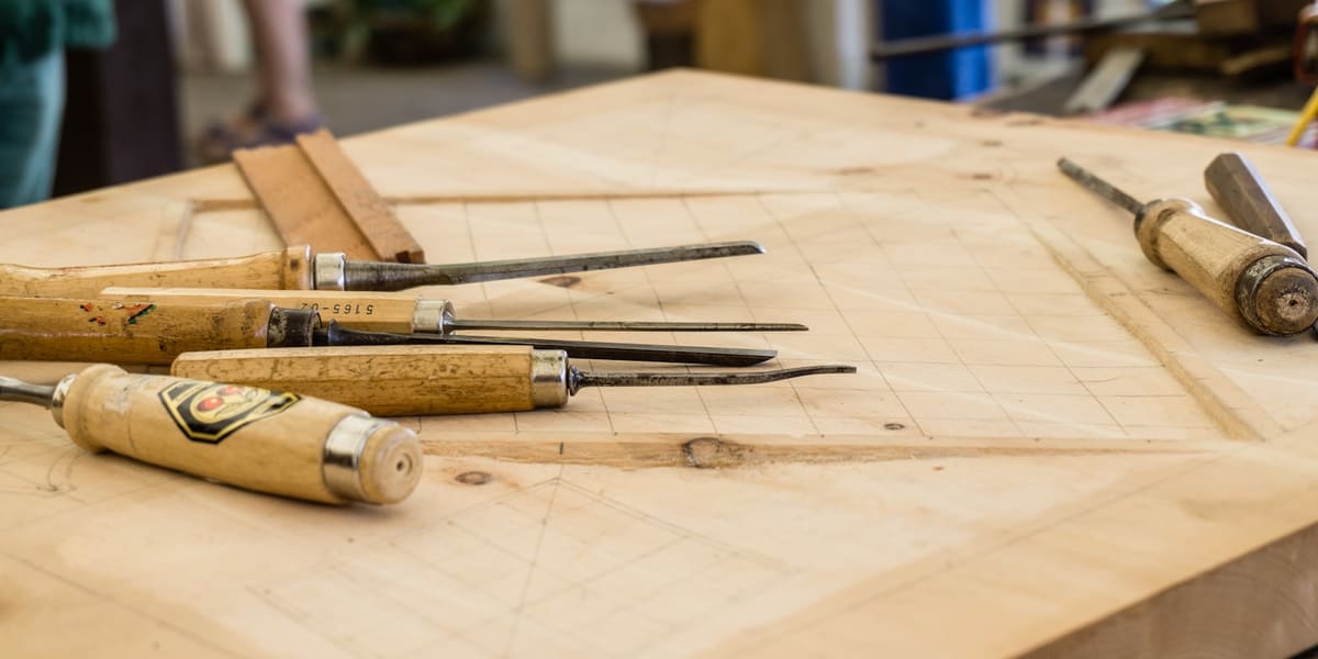 A neatly arranged set of traditional woodworking hand tools on a wooden workbench